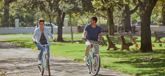 Homem e mulher a andar de bicicleta pelo jardim