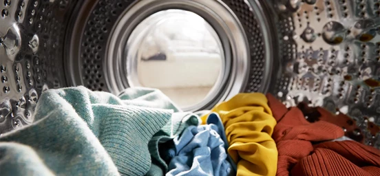Interior de uma máquina de lavar roupa com algumas peças coloridas
