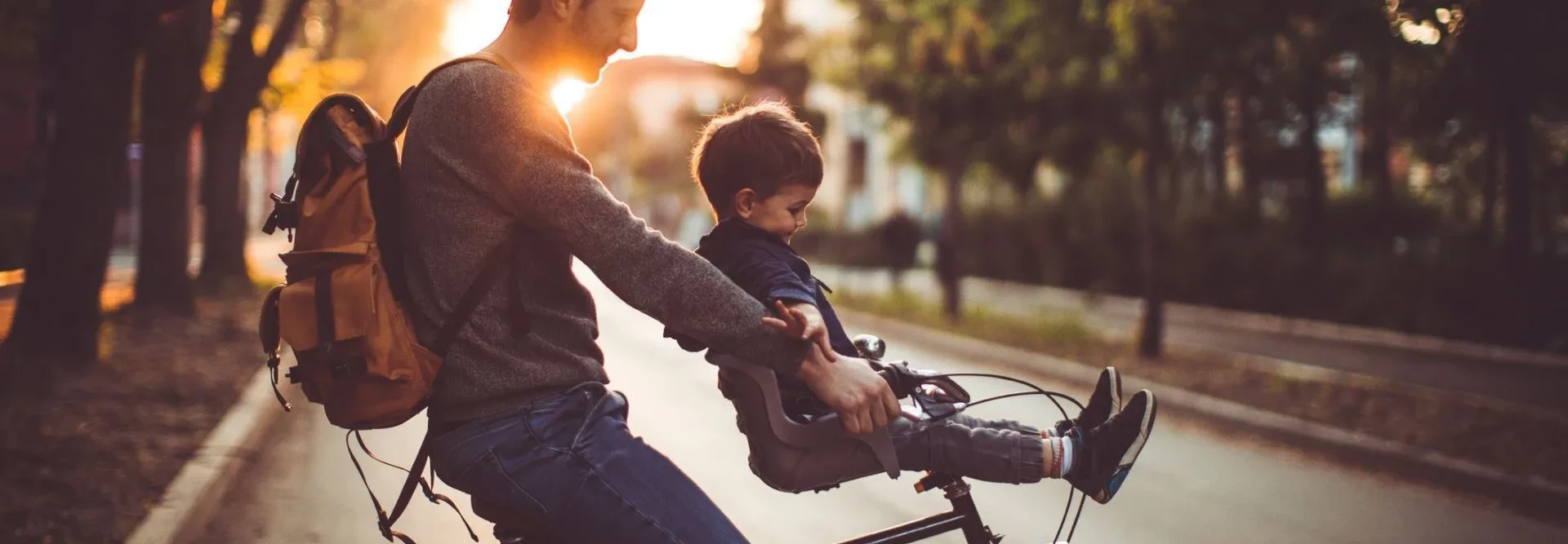 Homem e criança numa bicicleta com o pôr do sol