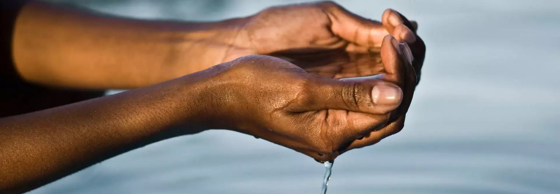 Mãos a segurar água de um rio