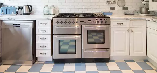 Cozinha onde se pode ver um fogão e uma máquina de lavar loiça