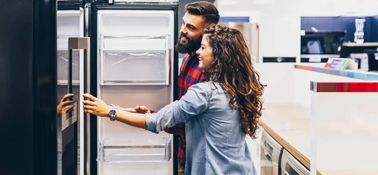 Casal numa loja de eletrodomésticos escolhe o seu novo frigorífico