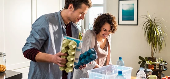 Homem e mulher a reciclar em casa caixas de ovos e garrafas de água