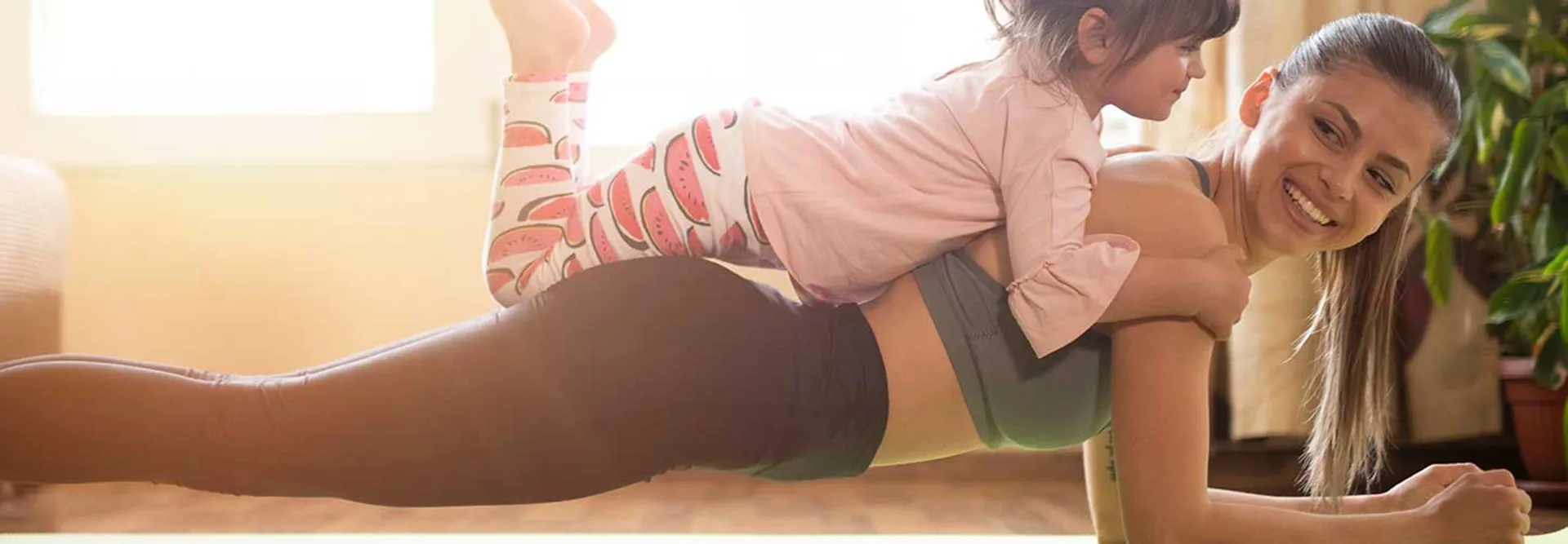 Mãe faz uma prancha com a filha deitada nas suas costas