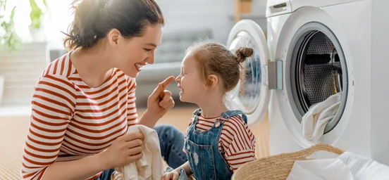Mulher e criança a brincarem enquanto lavam a roupa