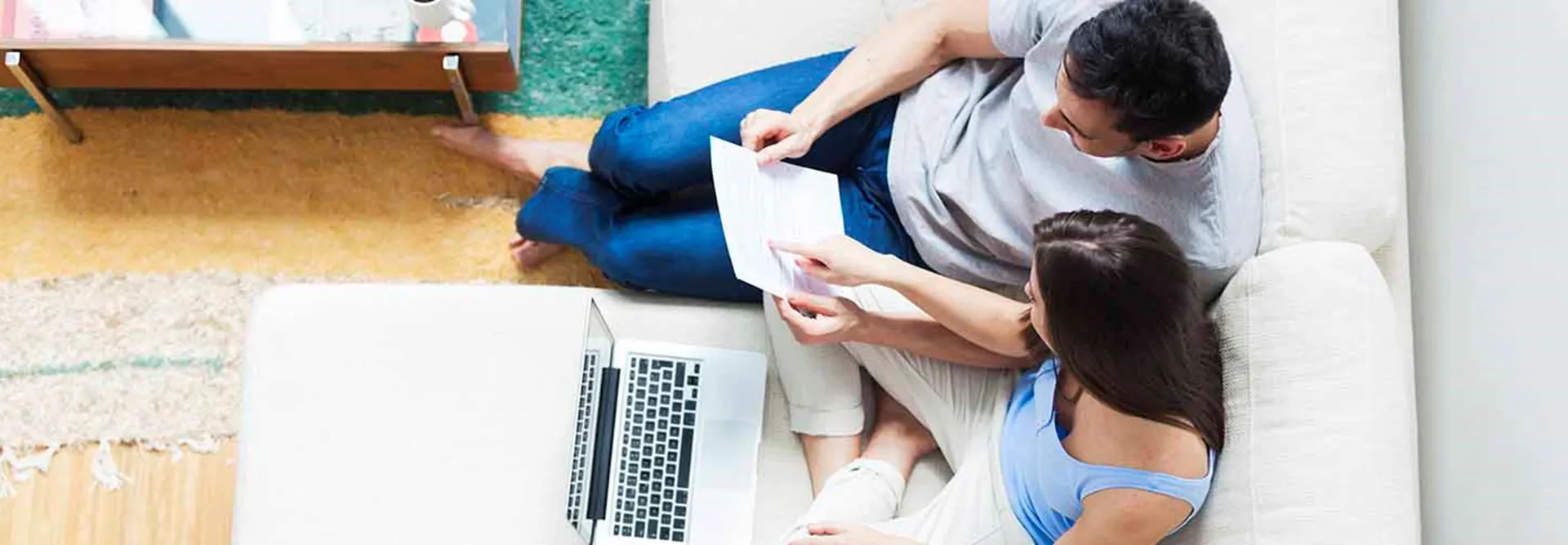 Homem e mulher com um computador nas pernas, sentados num sofá. analisam o seu certificado